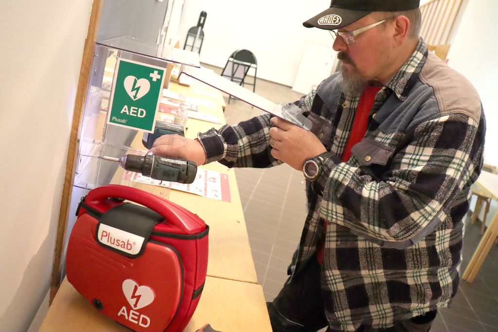 Erityisammattimies Jarmo Korhonen kiinnitti uuden defibrillaattorin läpinäkyvään kappiin Ristinkirkon ilmoitustaululle syyskuussa. Kuva: Teemu Leppänen